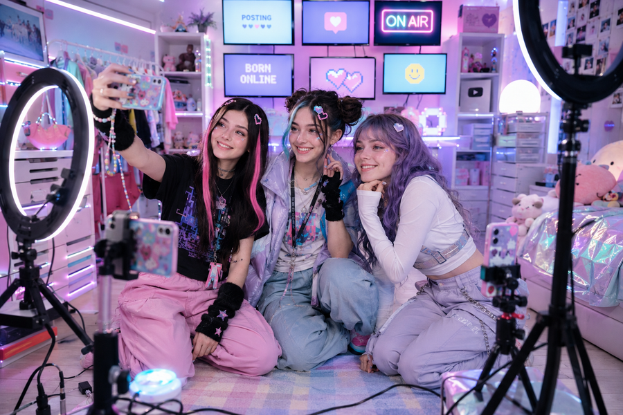 FYP — Lux, Remi and Wren in the bedroom studio, phones on ring-lights, screens behind them reading BORN ONLINE / POSTING / ON AIR